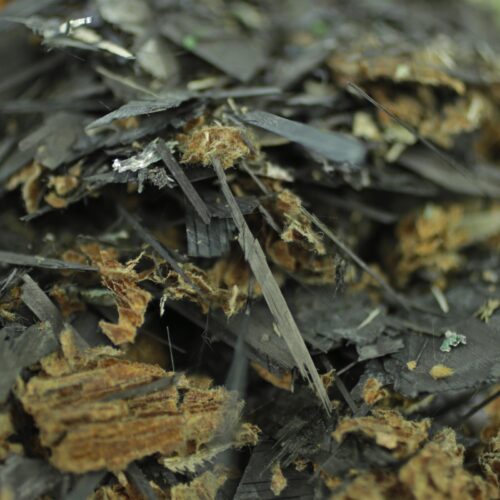 Nahaufnahme von zerkleinertem Carbonfaser-Verbundmaterial mit schwarzen Fasern und Harzresten